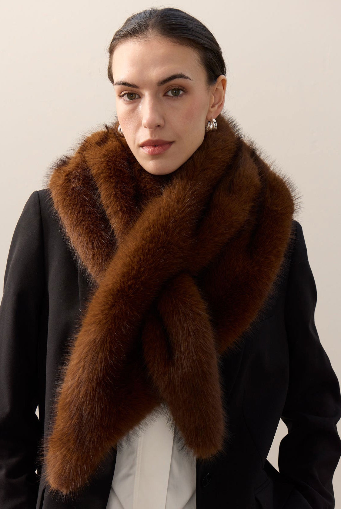 Helen Moore faux fur triangle scarf in mahogany, crossed and pulled through its slot over a black coat