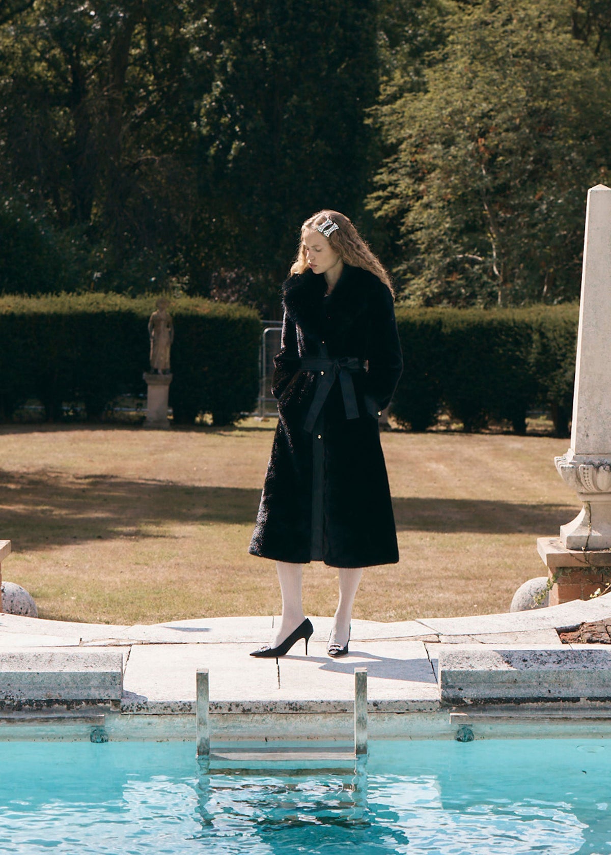Queens of Archive Styled beside a garden pool with black heels and a jewelled hair slide, belt tied in a bow at the waist