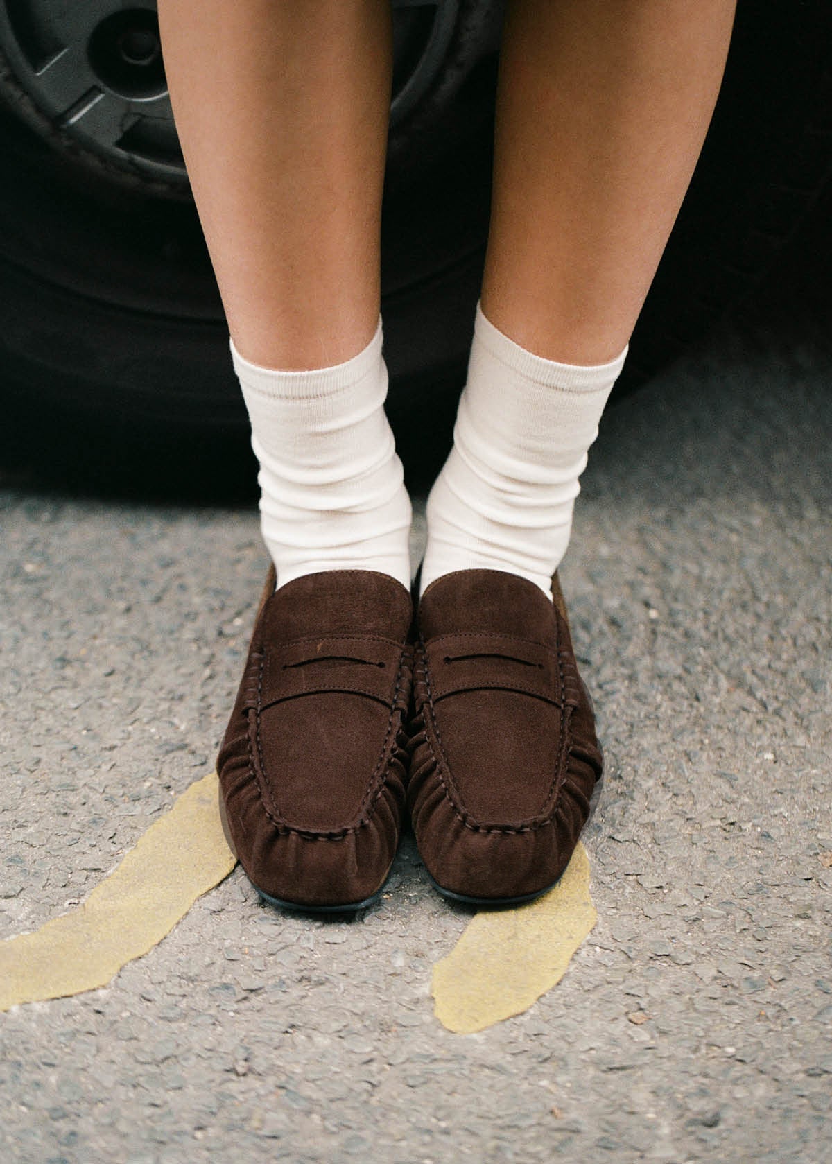 Alohas Worn on-model with white socks, seated on a kerb