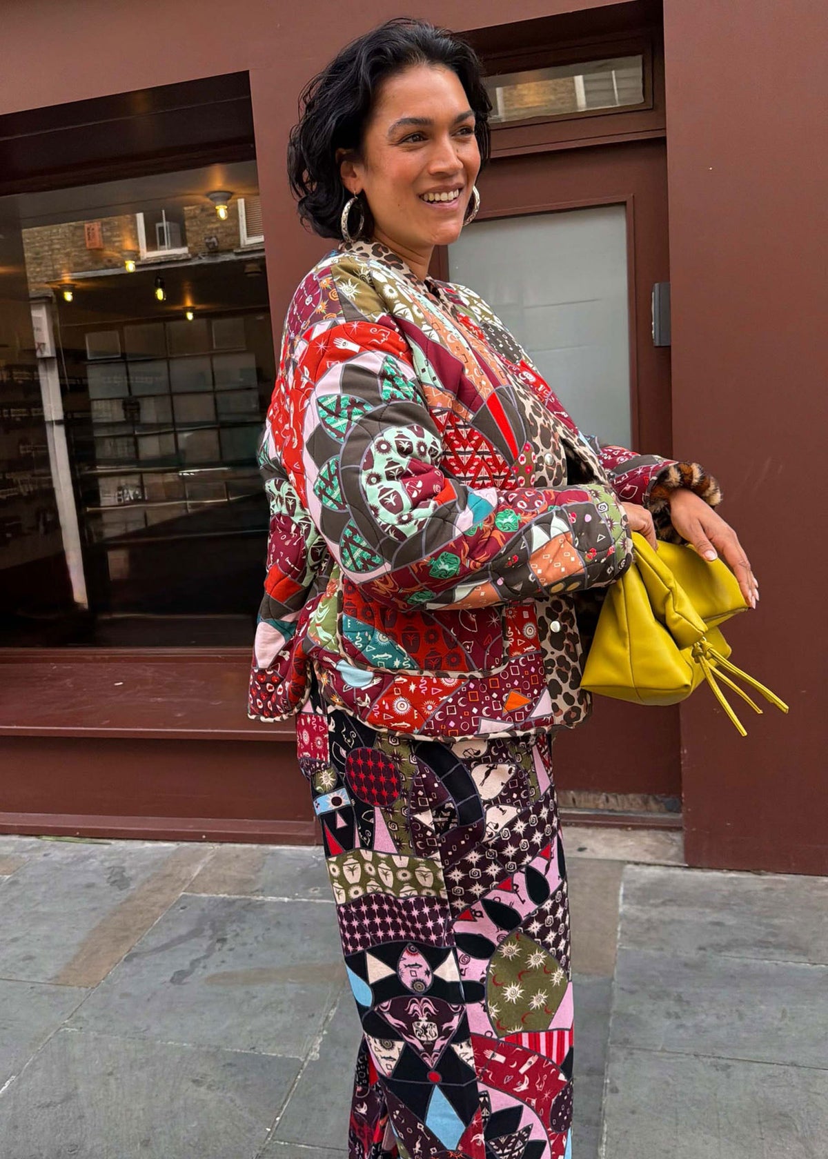 Never Fully Dressed Smiling in patchwork styled with matching print trousers and a yellow clutch