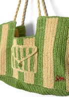 Angled close-up of rope handles attaching to the raffia body