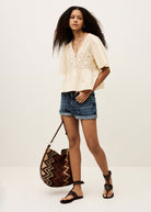 Full-length styling with denim shorts and a woven chevron shoulder bag