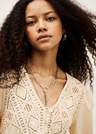 Close-up of the crochet yoke and front button placket with layered silver necklaces