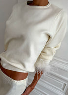 Close up of ribbed crew neck and pale feather trim