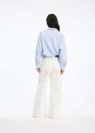 Back view, relaxed fit over white wide-leg trousers