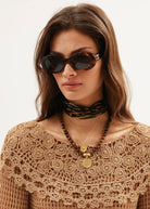 Worn at the throat with a tan crochet top and oval tortoiseshell sunglasses