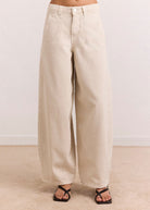 Side profile, curved barrel-leg silhouette in soft cream denim