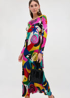 Flowing skirt in motion, styled with a black beaded top-handle bag and gold hoops