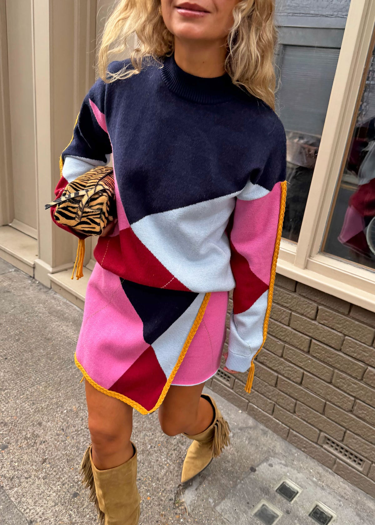 Never Fully Dressed Walking pose carrying a zebra print clutch with fringed suede boots