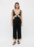 Full body styled with black satin trousers and gold-studded slides