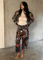 Patchwork jacket with matching trousers and strappy heels in a concrete setting