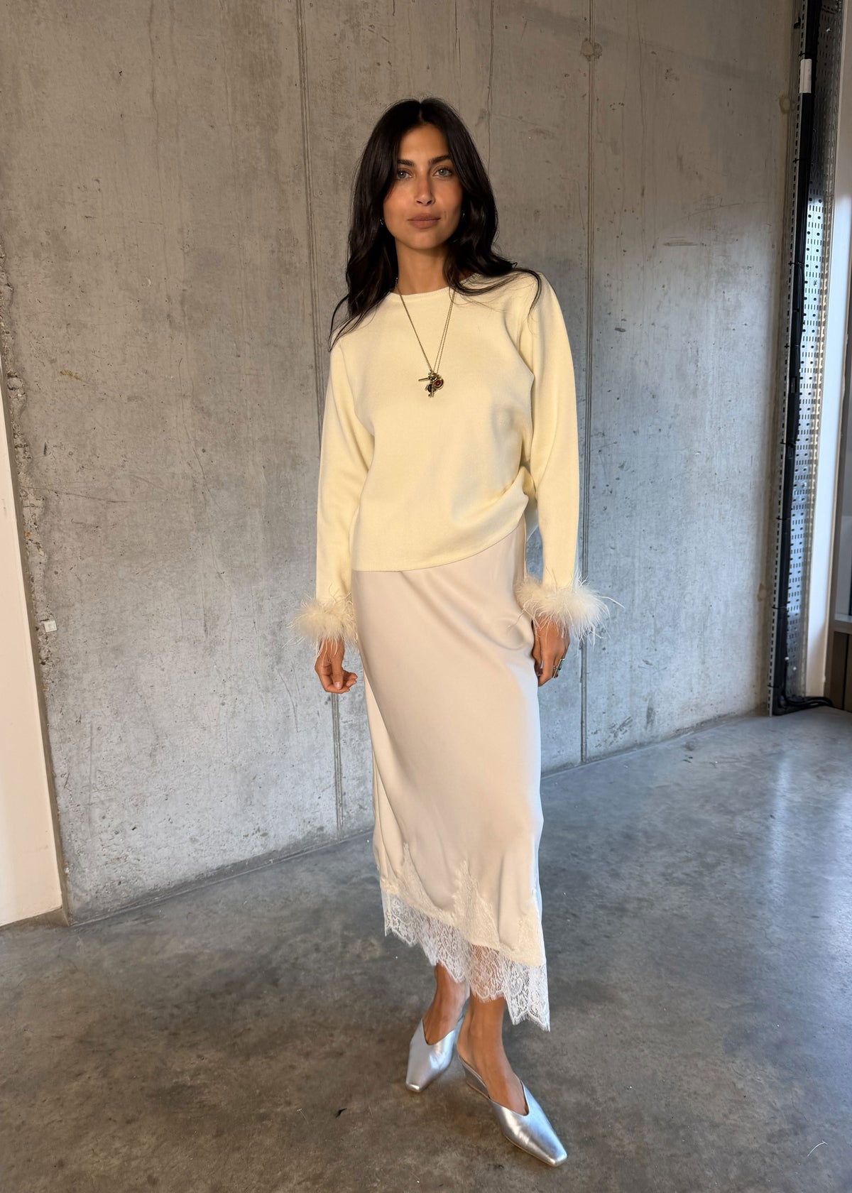 Never Fully Dressed Cream knit with silver pointed mules against a concrete wall