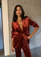 Single button blazer in rust red velvet worn open with a pendant necklace