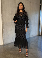 Styled with black velvet clutch and strappy sandals against concrete