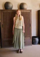 Lifestyle shot in Mykonos with carved wooden cabinet backdrop and sage skirt