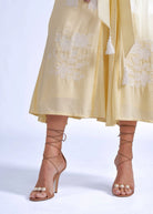 Waist detail, white cross-stitch floral motif beneath the sash belt