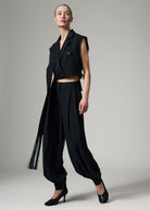 Walking pose with a cropped waistcoat and black leather heels, the wide leg swinging as she moves