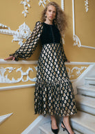 Angled pose with black patent slingbacks, covered velvet buttons down the bodice