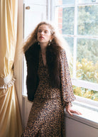 Closer crop with a dark fur stole over the buttoned V-neck bodice and gathered sleeve