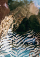 Close crop through glass reflections, zebra stripes and faux fur collar at the shoulder