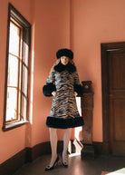 Wider view with a black faux fur hat and white tights, flared line and deep fur cuffs