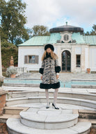 Styled outdoors on pale stone steps by a pool, knee length with a black faux fur hem