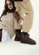Worn in the snow with beige quilted trousers and dark socks, cropped leg shot