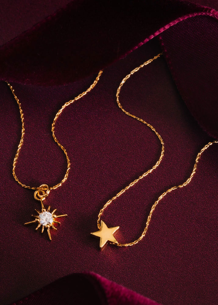 Orelia Flat-lay on burgundy satin, alongside a crystal starburst pendant on matching chain