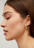 On-ear styling shot showing the ivory enamel against natural light