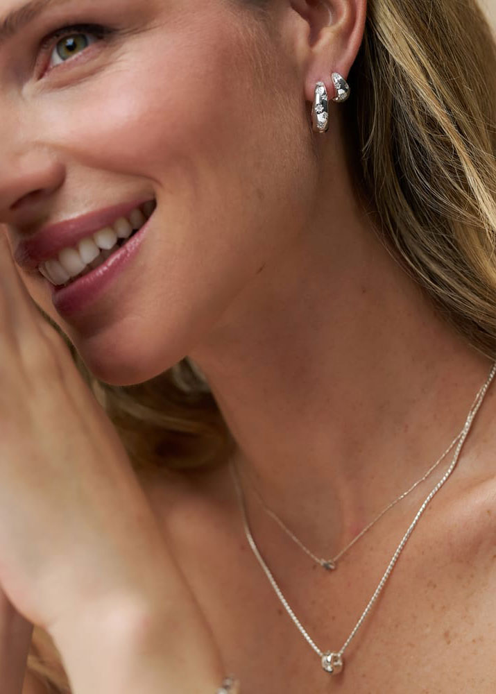 Orelia Worn doubled up in the lobe, layered silver chains and a bead pendant below