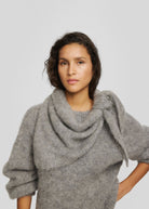 Draped over the shoulders and tied at the side, worn with a matching grey knit